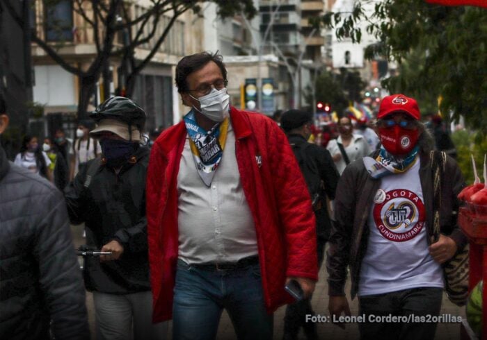 Por qué pelean entre ellos los 21 miembros del comité ejecutivo nacional de la Central Unitaria de Trabajadores Group of masked protesters walking on a city street; man in a red jacket and mask leads the scene. - Por qué pelean entre ellos los 21 miembros del comité ejecutivo nacional de la Central Unitaria de Trabajadores