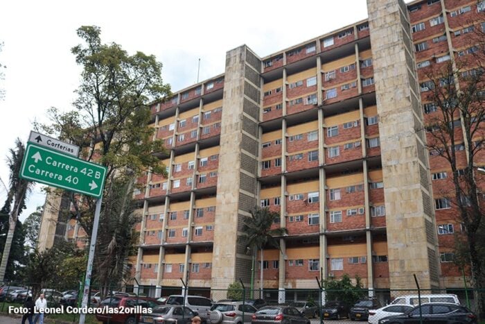 La historia de imponente hacienda sobre la que se levantó Corferias y su barrio vecino Quinta Paredes Large brick apartment building with multiple balconies behind a fence; street signs read Carrera 42B and Carrera 40 in the foreground. - La historia de imponente hacienda sobre la que se levantó Corferias y su barrio vecino Quinta Paredes