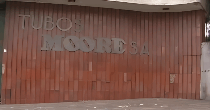 Moore: la fábrica de tubos y ladrillos que desapareció para darle paso al Portal 20 de julio Pink exterior wall with vertical panels and large white 3D letters forming a storefront sign. - Moore: la fábrica de tubos y ladrillos que desapareció para darle paso al Portal 20 de julio